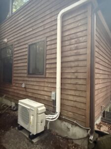 An outdoor Daikin ductless mini-split condenser unit installed with refrigerant lines running up the wall by Cummings Inc. in Puyallup, WA.