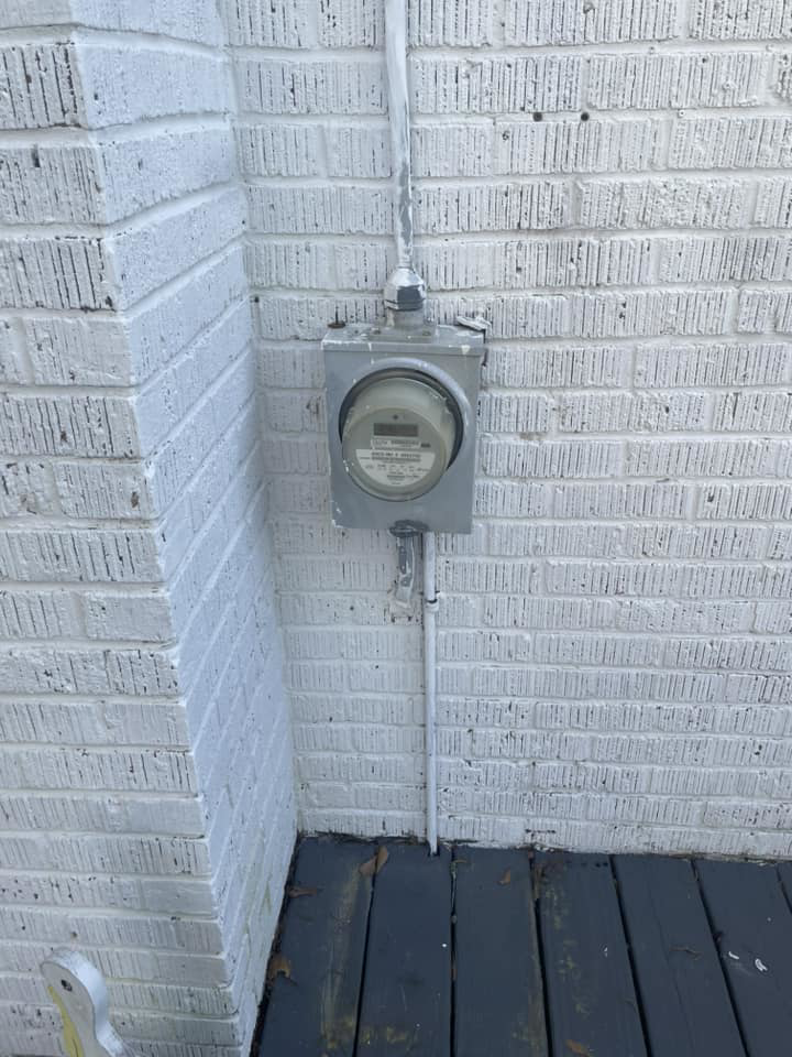 An outdoor electric meter and conduit on a brick building, indicating electrical service by Charging Rhino Electric in Mobile, AL