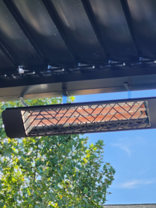 An outdoor electric patio heater installed under a modern patio roof by ATW Electric in Kansas City, MO.