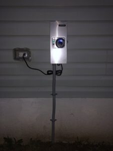 An outdoor electrical box with a camera or sensor and an adjacent outlet, installed by Surge Electric LLC in Youngstown, OH.