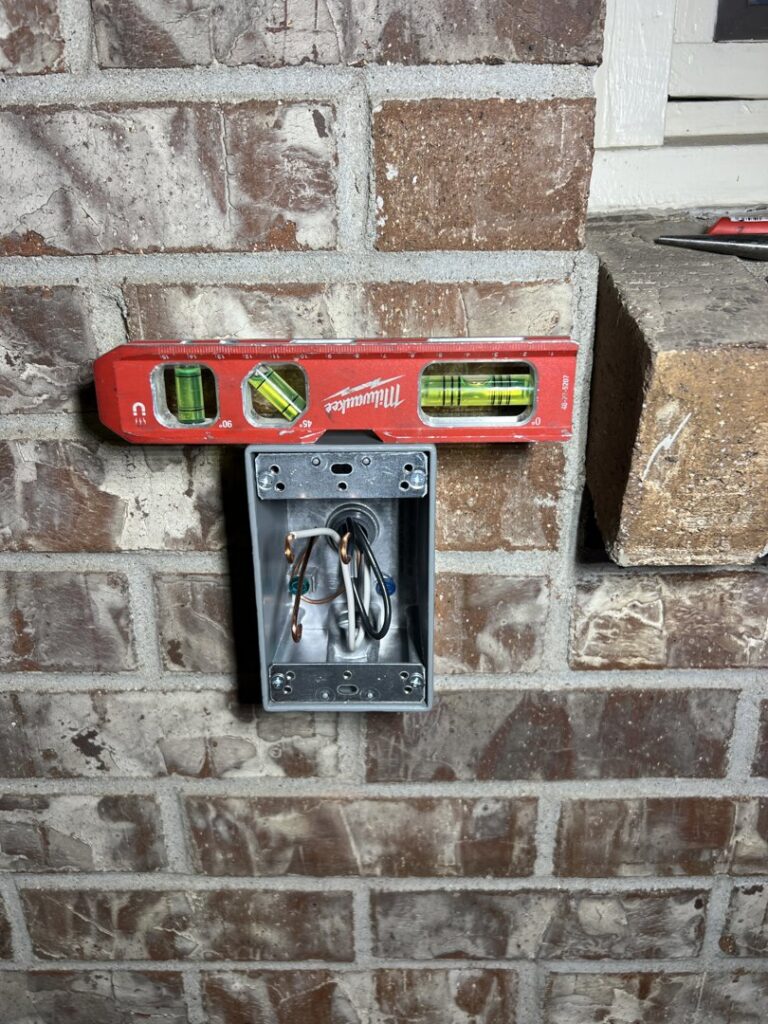 An outdoor electrical box being installed on a brick wall by Sparrow Electric, LLC in Denver, CO.