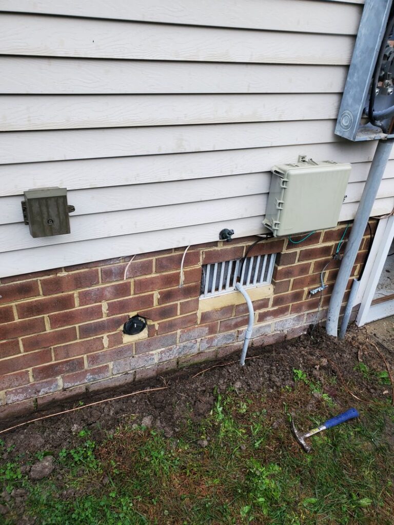 Outdoor electrical conduit and grounding wire installation along the side of a house by Neptune Electric in Virginia Beach, VA.