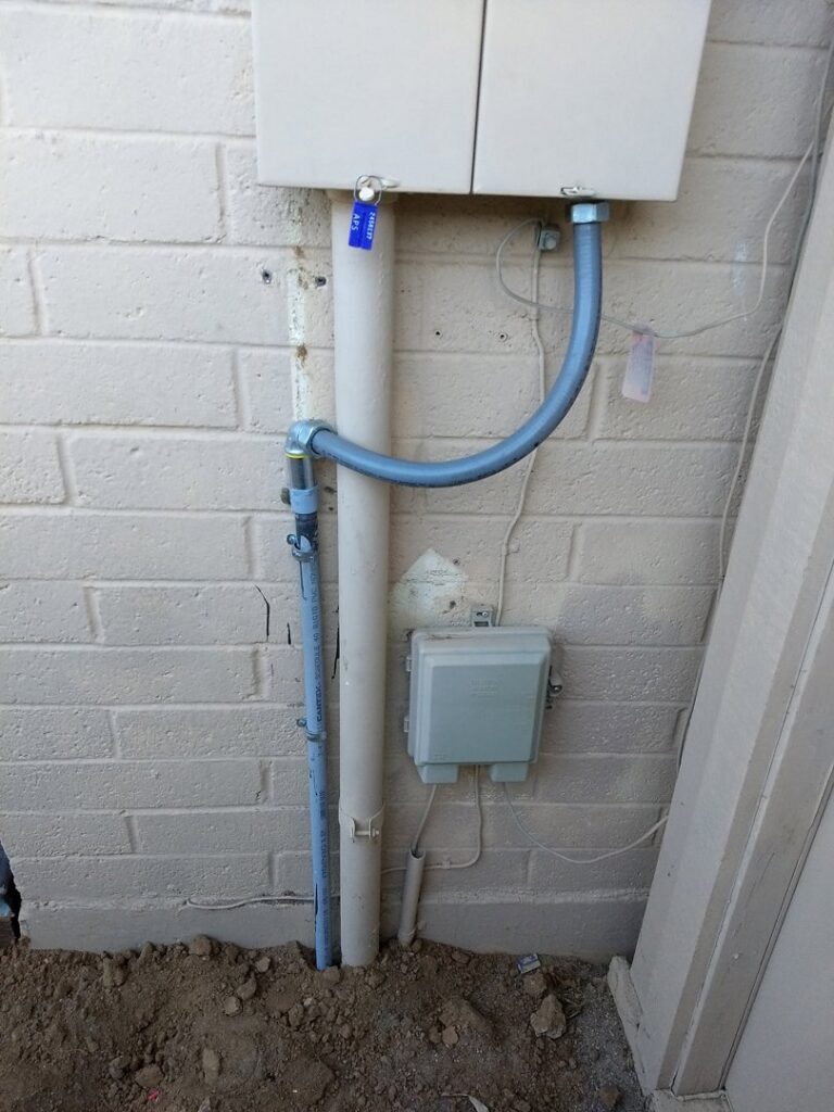Outdoor electrical conduit and junction boxes installed on a brick wall by Turn It On Electric in Phoenix, AZ