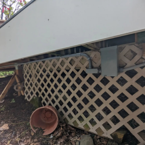 A wider view of outdoor electrical conduit and junction boxes neatly installed under a deck by Alt Electric LLC in Federal Way, WA.