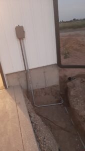 Outdoor electrical conduit being installed along a building and underground by Ostberg Electrical Solutions in Idaho Falls, ID.