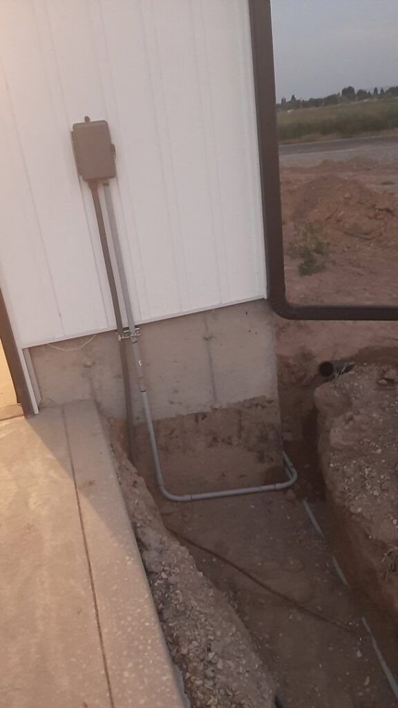 Outdoor electrical conduit being installed along a building and underground by Ostberg Electrical Solutions in Idaho Falls, ID.