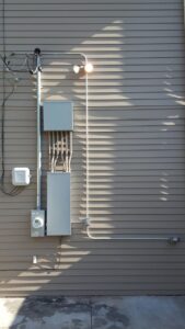 Outdoor electrical conduit, panels, and a light fixture installed on a building by Red Earth Electric LLC in Oklahoma City, OK.