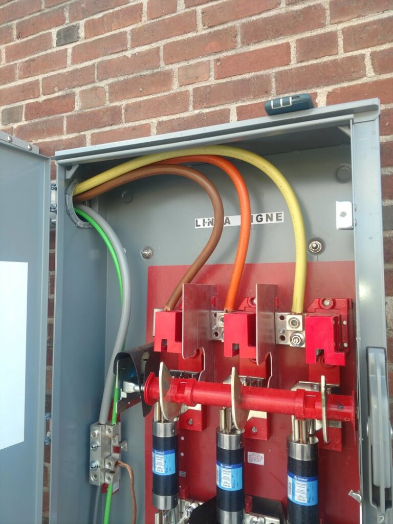 Close-up of an outdoor electrical disconnect box with heavy gauge wiring and fuses, installed by Icon West Corporation Electrical Contractors in Springfield, MA.