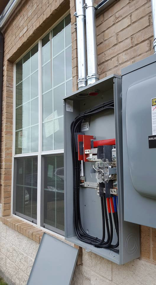 An outdoor electrical meter box installation on a brick wall by Genesys Electrical Contractors in Dallas, TX