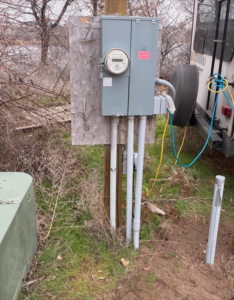 An outdoor electrical meter box with conduits installed on a wooden post by Tier 1 Electric in Boise, ID.