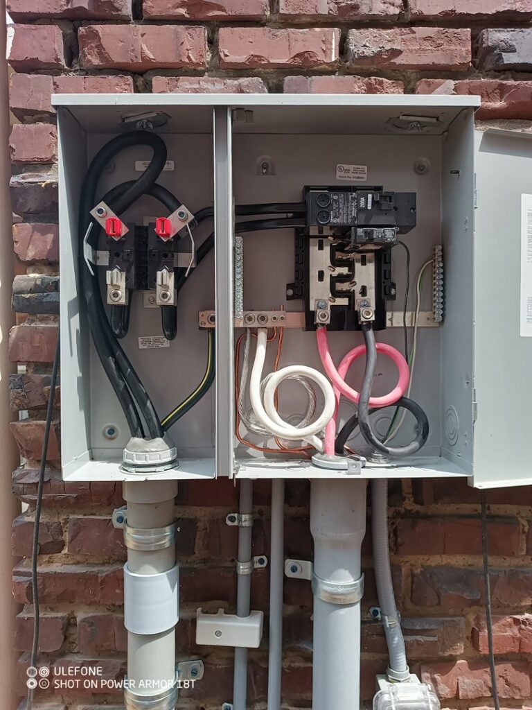 An outdoor electrical meter box with exposed wiring on a brick wall, serviced by Elemental Electrical in Chattanooga, TN.