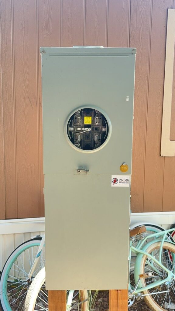 An outdoor electrical meter box with the AC-DC Electric logo, indicating professional installation in Severance, CO.