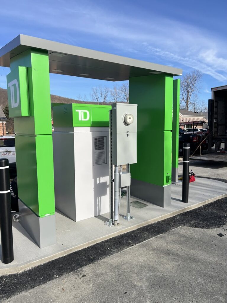 An outdoor electrical meter and conduit system installed next to a TD bank building by Peeler Electric Light & Power in Merrimack, NH.