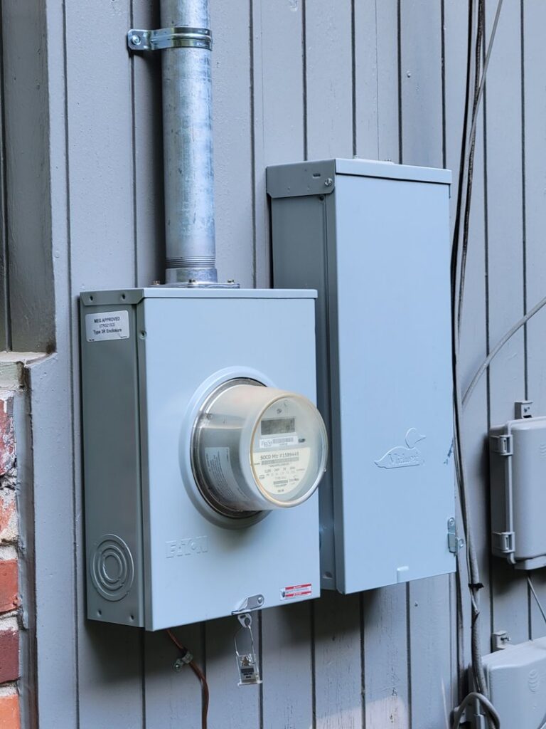 An outdoor electrical meter and service panel installed on the side of a building by 8Thirty Electric, Inc. in Johns Creek, GA.