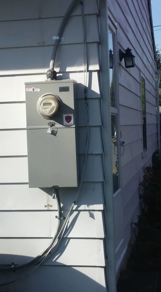An outdoor electrical meter and service panel installed on the side of a house by Dragons Electric in Schenectady, NY