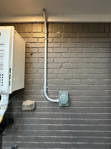 An outdoor electrical outlet and conduit professionally installed on a brick wall by AHM ELECTRIC in Houston, TX.