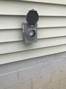 An outdoor electrical outlet or connection box installed on house siding by Bacon Electric, LLC in Concord, NH.