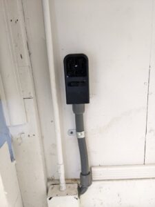 An outdoor electrical outlet and conduit installed on a white exterior wall by Jeremy Electrical in Roeland Park, KS.