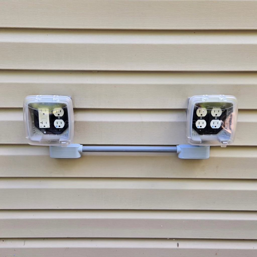 Newly installed outdoor electrical outlets with weatherproof covers on a building's siding by Maiolo Electric in Pittsburgh, PA.