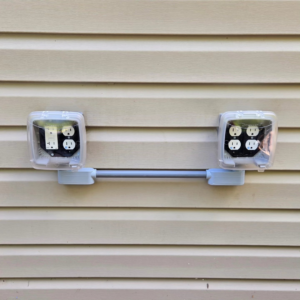 Newly installed outdoor electrical outlets with weatherproof covers on a building's siding by Maiolo Electric in Pittsburgh, PA.