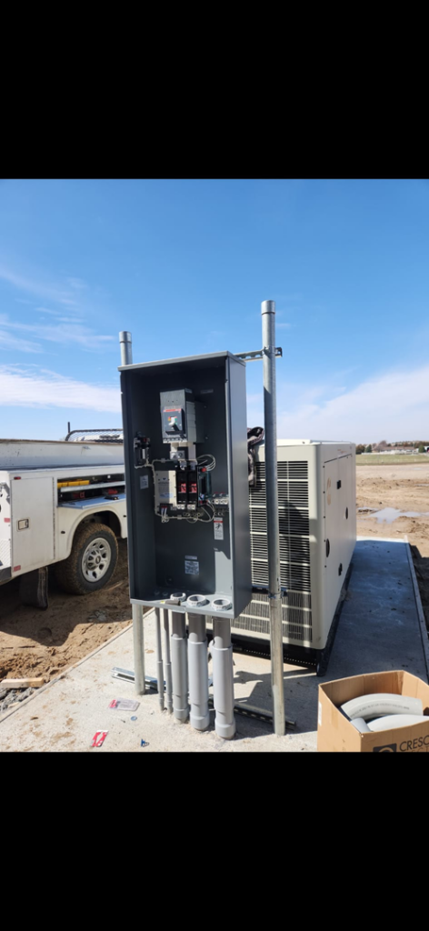 An outdoor electrical control panel and conduits installed next to a generator by Island Electric in Grand Island, NE.