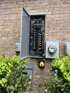 An open outdoor electrical panel showing wiring and circuit breakers, serviced by Big City Lighting and Electric in Houston, TX.