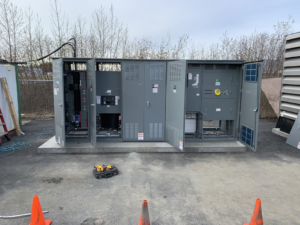 Outdoor electrical panel and switchgear installation by Alyeska Electric in Anchorage, AK, with tools on the ground.