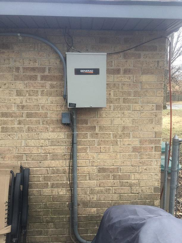 An outdoor electrical panel or generator transfer switch installed on a brick wall by Mr. Electric of Rogers in Rogers, AR.