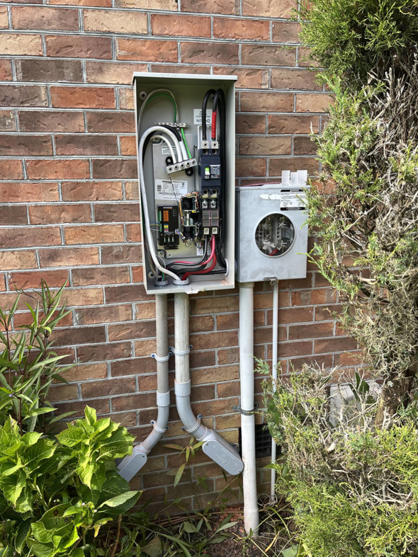 An outdoor electrical panel and meter box on a brick wall, showing wiring by Strother & Son Electric in Mount Pleasant, SC.