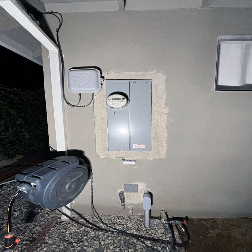 An outdoor electrical service panel and meter on a house wall at night, installed by Fuse Service HVAC & Electrical Sacramento, CA