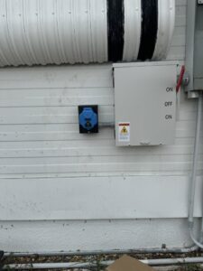An outdoor electrical panel and a blue industrial outlet installed on a building by River Electric, LLC in Greenville, SC.