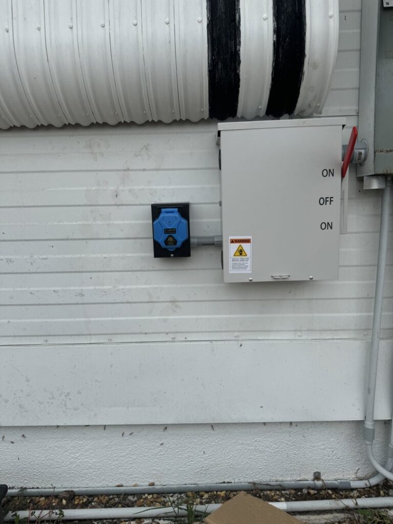 An outdoor electrical panel and a blue industrial outlet installed on a building by River Electric, LLC in Greenville, SC.