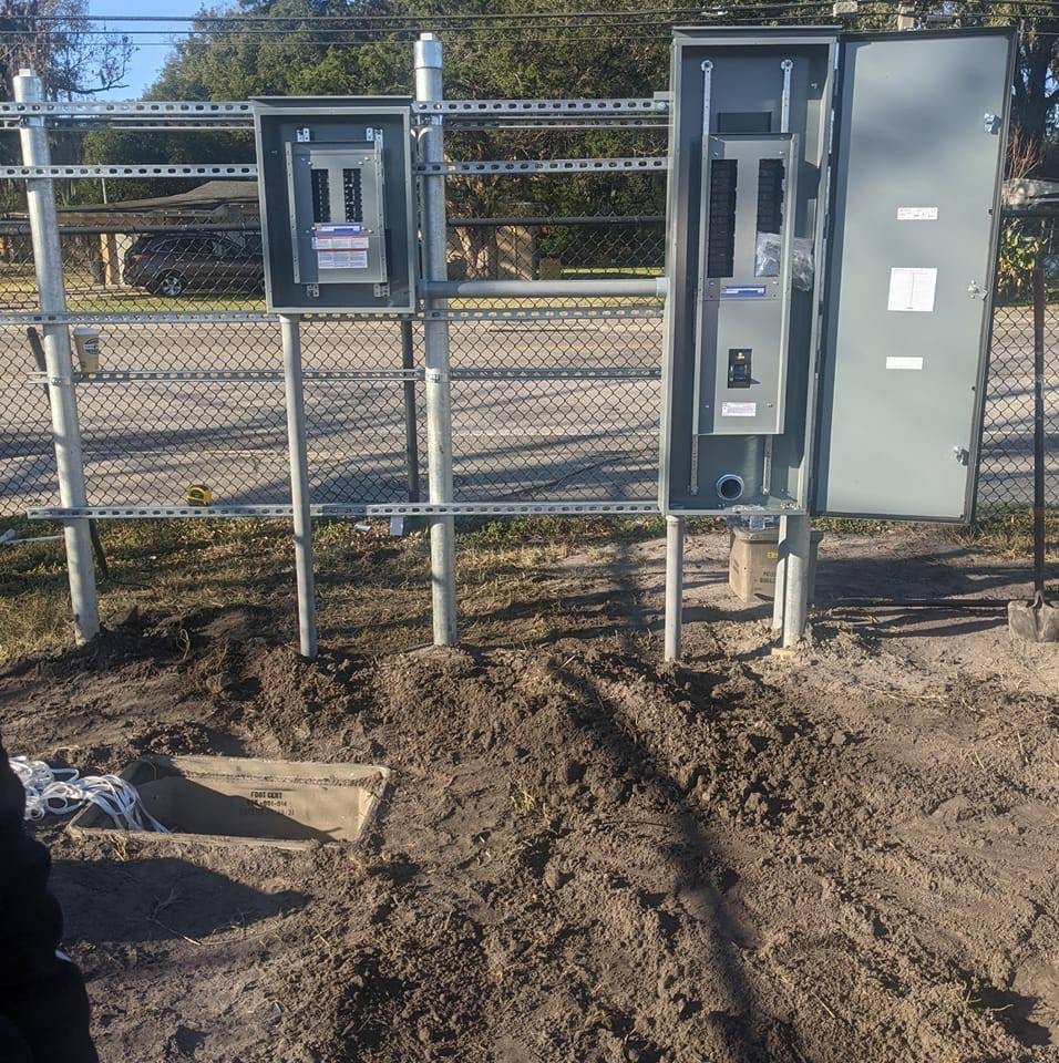 Two outdoor electrical panels mounted on posts with disturbed ground, indicating new electrical service installation by GOBE LLC in Columbia, MO.
