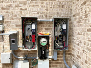 Outdoor electrical service entrance with multiple meters and disconnects on a brick wall by Ace Electric Inc. in Valdosta, GA.