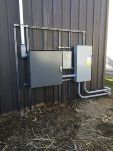 An outdoor electrical service installation with meter and panels on a corrugated metal wall by Electric Today in Indianapolis, IN.