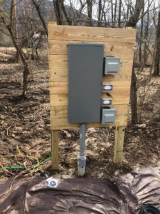 Outdoor electrical service panel and outlets installed on a wooden board by Jon Chamberlain Electrical Services in Saxton, PA.