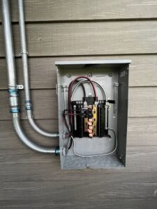 An outdoor electrical sub-panel with conduits installed on the side of a house by kt_electricalcontractors in Spokane Valley, WA