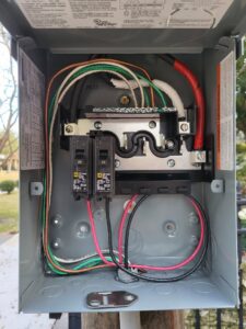 An open outdoor electrical sub-panel or disconnect box with wiring and breakers, installed by Ozzy Electric in Jacksonville, FL.