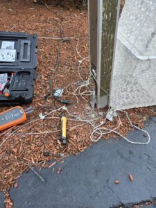 Outdoor electrical wiring and tools like a multimeter and voltage tester on the ground by DHJ Electric in Methuen, MA.
