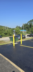 An outdoor electric vehicle charging station with yellow bollards under a clear sky by Pittsburgh Electric & Maintenance in Pittsburgh, PA