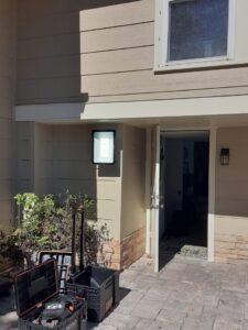 An outdoor floodlight installed above a doorway with an electrician's toolbox nearby by Positricity in Clearwater, FL.