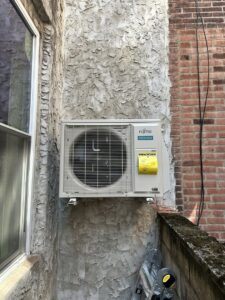 An outdoor Fujitsu Airstage mini-split unit installed on a building wall by Mueller Mechanical HVAC in Philadelphia, PA.