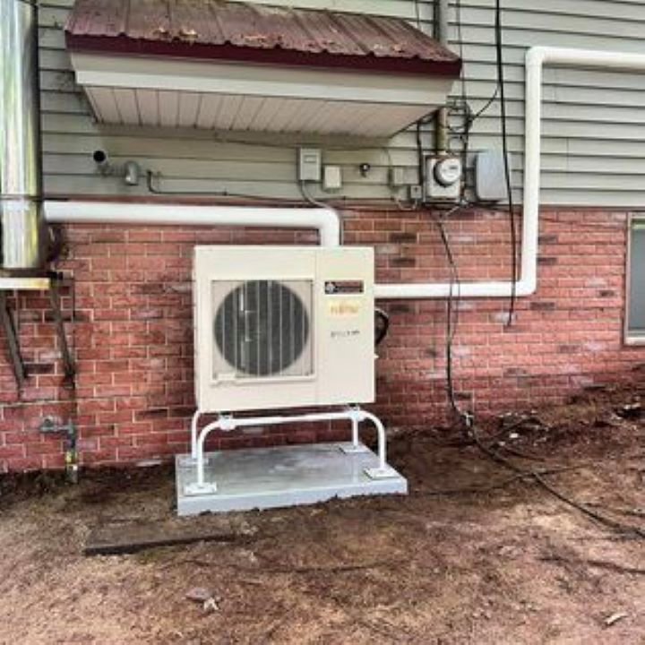 An outdoor Fujitsu Airstage heat pump unit installed against a brick wall by Advanced Comfort LLC in Concord, NH.