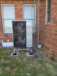 An outdoor GE HVAC unit installation next to a brick building by Black Tie Home Services in Springfield, IL