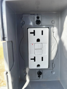 A close-up view of a newly installed outdoor GFCI electrical outlet by Flores power solutions in El Paso, TX.