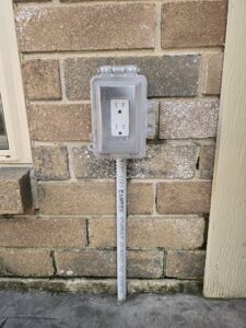 An outdoor GFCI electrical outlet in a weatherproof box installed on a brick wall by Ponce Electric in Houston, TX