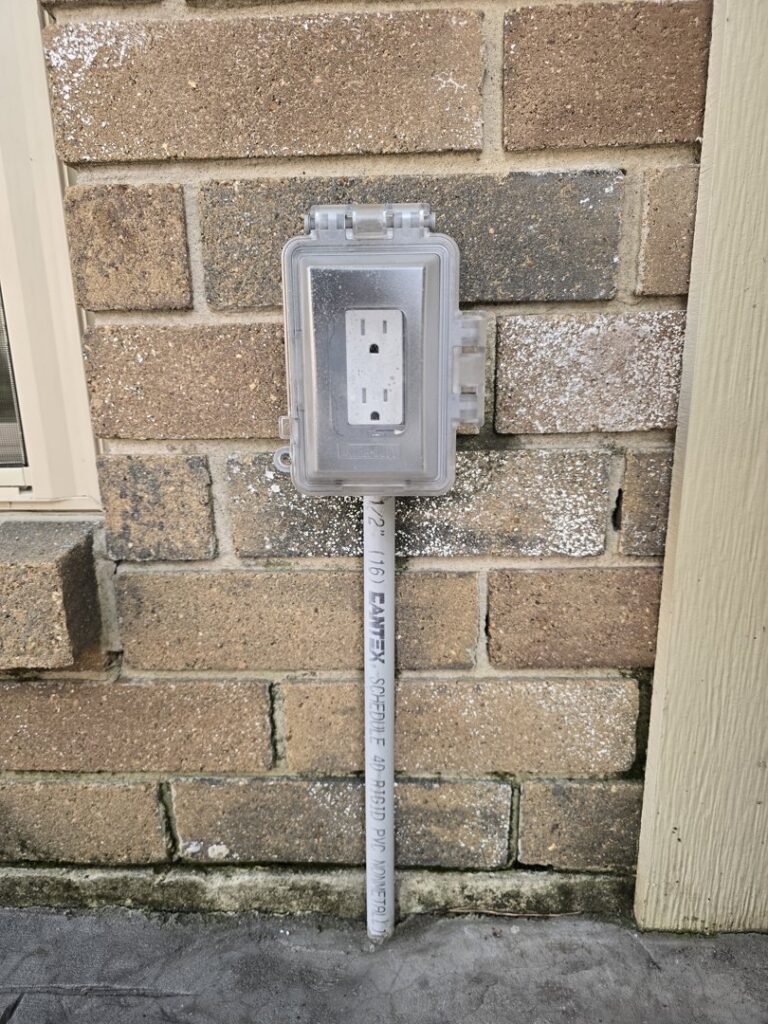 An outdoor GFCI electrical outlet in a weatherproof box installed on a brick wall by Ponce Electric in Houston, TX