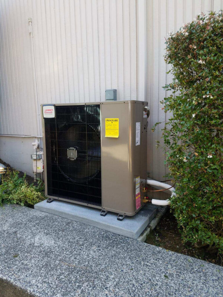 An outdoor Coleman heat pump unit newly installed next to a residential building by Cummings Inc. in Puyallup, WA.