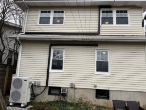 An outdoor heat pump condenser unit with refrigerant lines installed on the side of a house by GrinHouse HVACR in La Grange, KY.