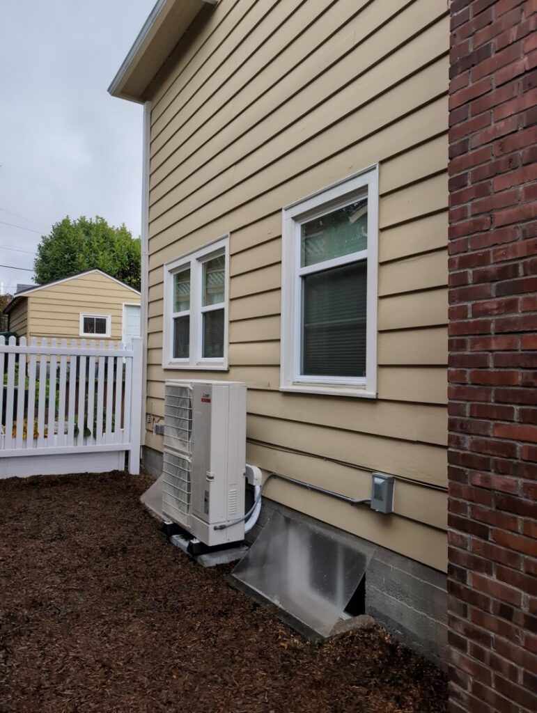 An outdoor heat pump unit installed next to a residential home by Progressive Comfort Solutions in Seattle, WA.